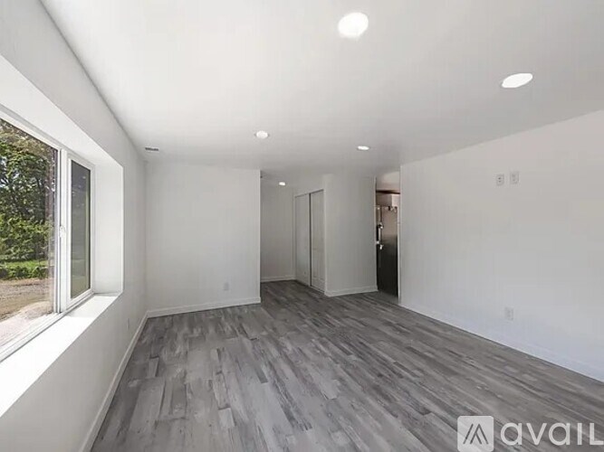 A spacious room with wooden flooring and white walls.