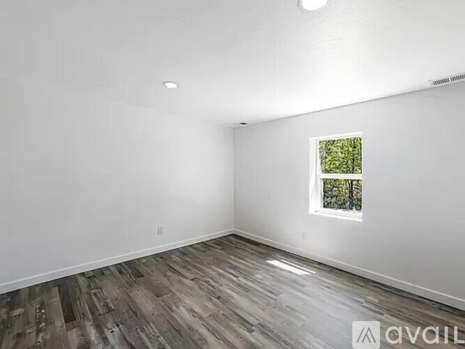 A room with a window and wooden flooring is available for rent.