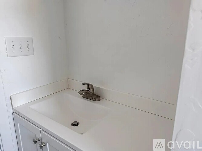 A white bathroom sink with a silver faucet and a white cabinet.