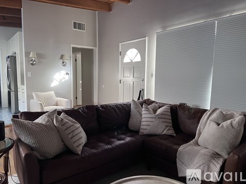 A brown couch with white pillows sits in a living room.