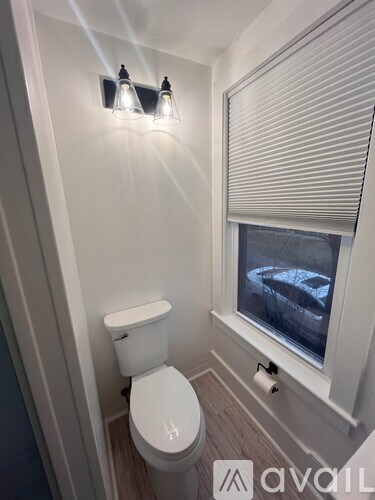 A white toilet in a small bathroom with a window.