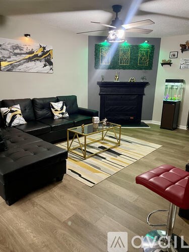 A living room with a black couch, a fireplace, and a rug.