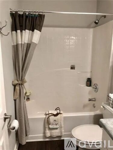 A white toilet sits next to a bathtub in a small bathroom.