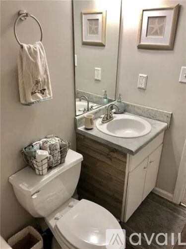 A bathroom with a toilet, sink, and mirror.