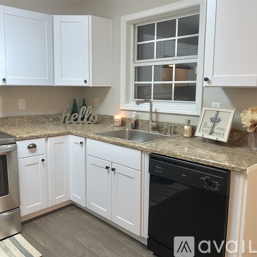 A kitchen with white cabinets and a black dishwasher.