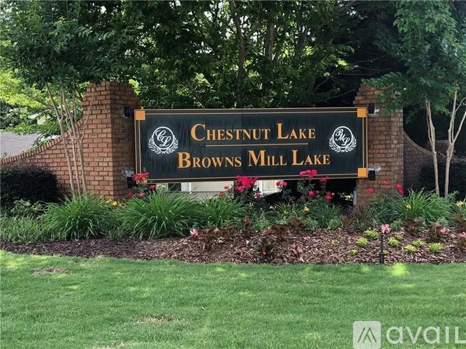 A sign for Chestnut Lake Browns Mill Lake is displayed in front of a brick wall.