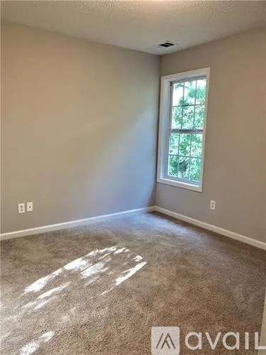 A room with a window and a carpeted floor.
