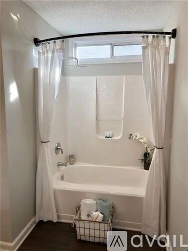 A white bathroom with a tub and a window.