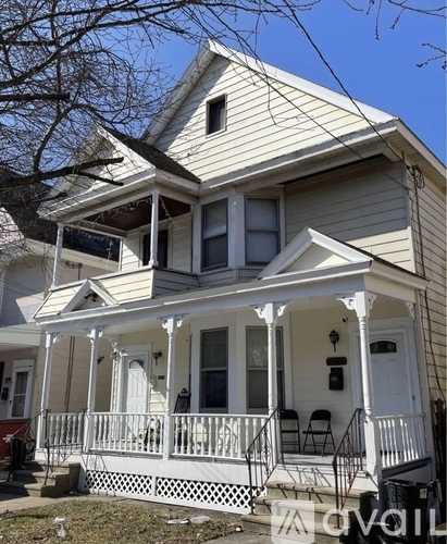 A two-story house with a white porch and black railings.