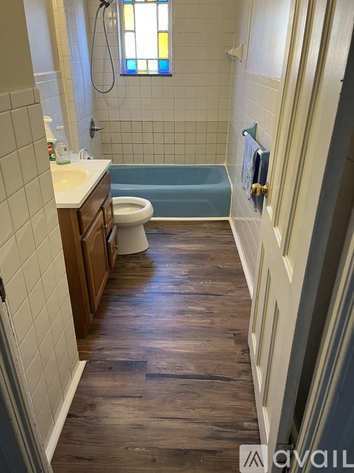 A bathroom with a wooden floor and white tiles.