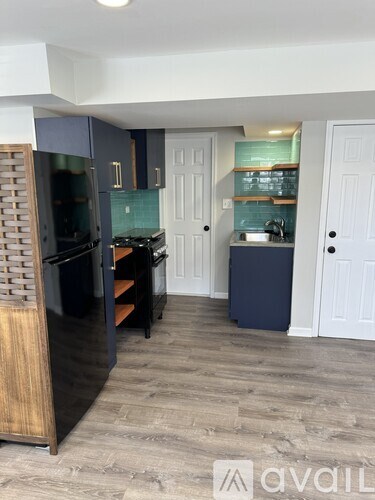 A kitchen with a black refrigerator and wooden cabinets.