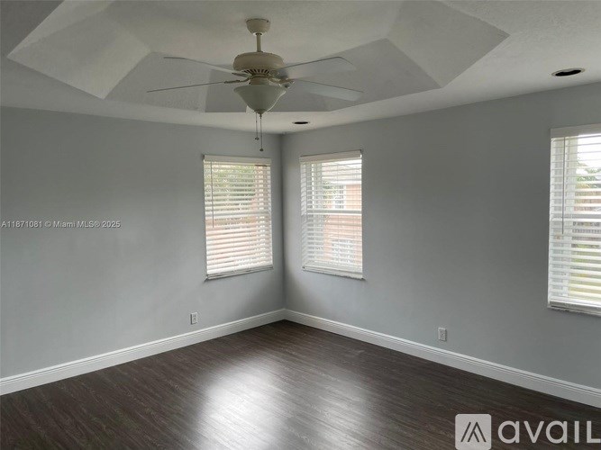 A room with a ceiling fan and two windows.