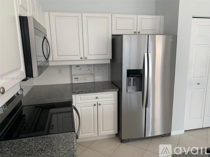 A kitchen with a stainless steel refrigerator and white cabinets.