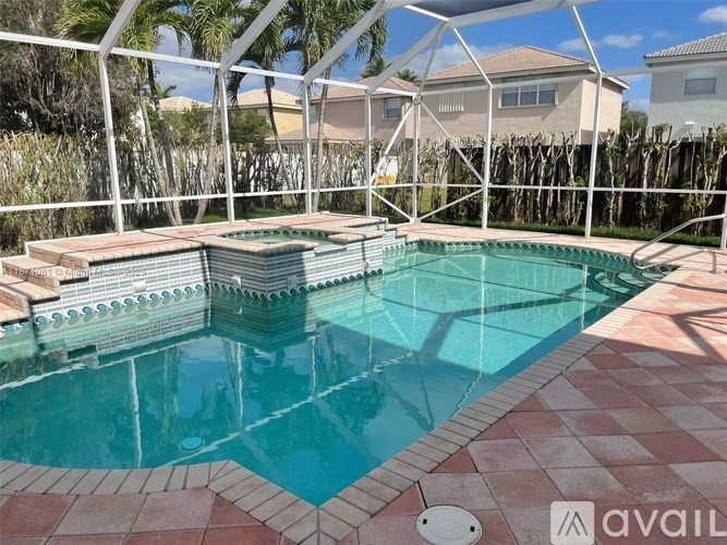 A pool with a red and white tiled edge and a white fence surrounding it.