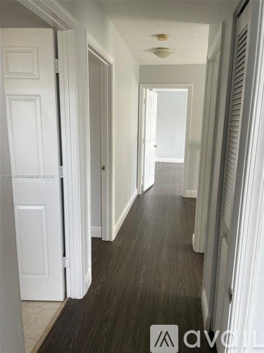 A hallway with white doors and a wooden floor.