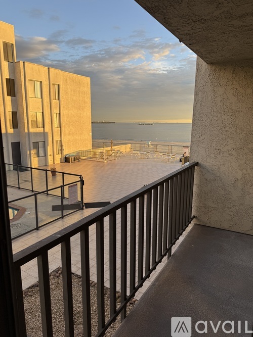 A balcony with a metal railing overlooks a body of water with boats.