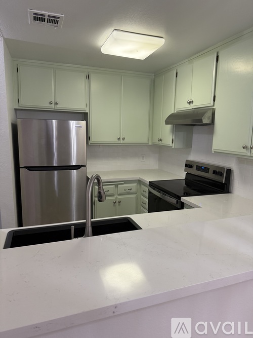 A kitchen with white cabinets and a stainless steel refrigerator.