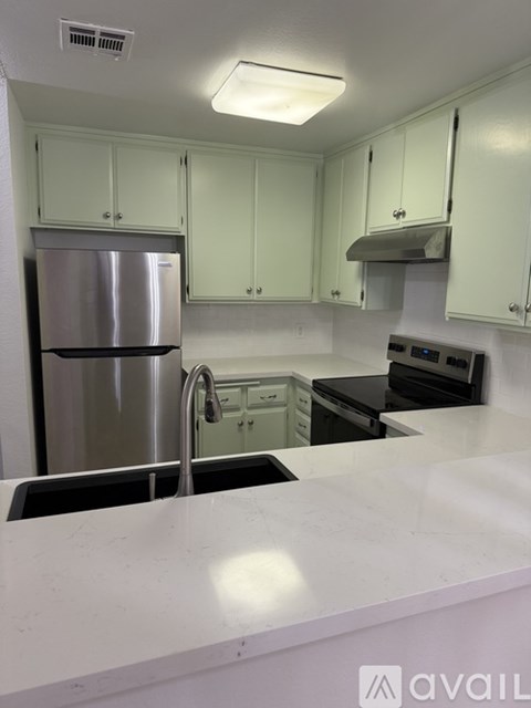 A kitchen with white cabinets and a stainless steel refrigerator.