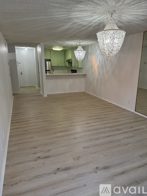 A spacious room with wooden flooring and a chandelier hanging from the ceiling.