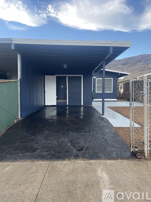 A blue building with a white door and a metal fence.
