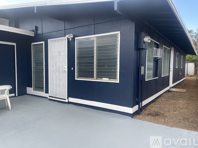 A blue house with white trim and a white bench in front.