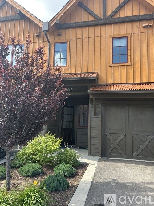 A house with a brown wooden exterior and a grey garage door.
