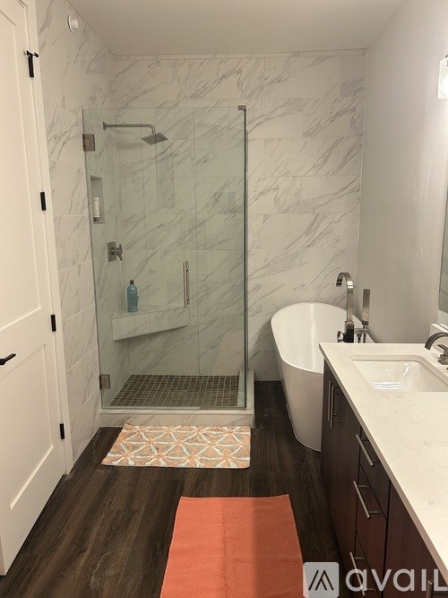 A bathroom with a marble wall and a glass shower stall.