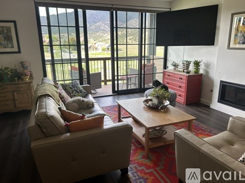 A living room with a couch, a chair, a coffee table, and a dog.