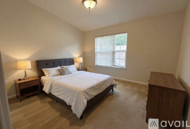 A bedroom with a bed, nightstand, and window.