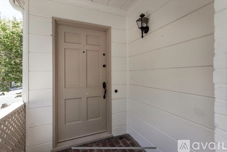 A white door with a black handle is on the left side of a white wall.