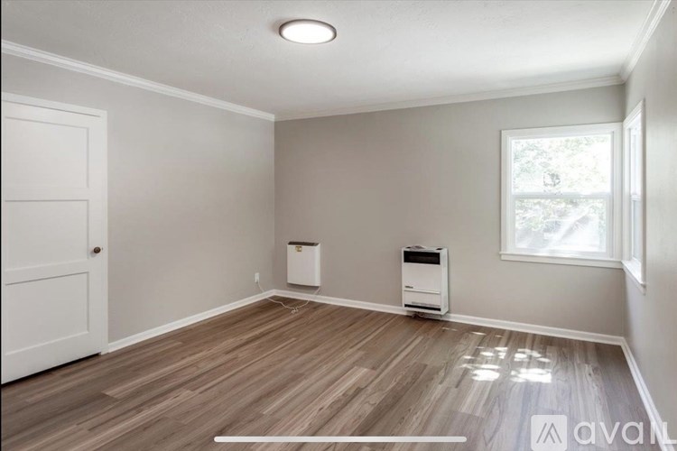 A room with wooden flooring and a window letting in natural light.