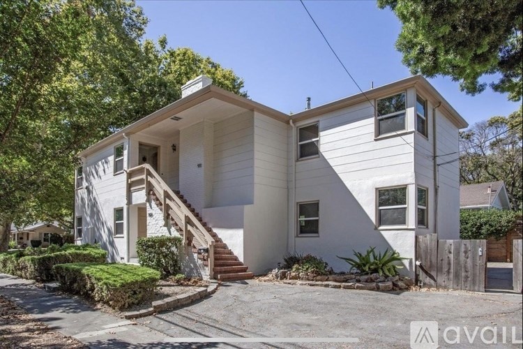 A white two-story house with a staircase leading to the second floor.