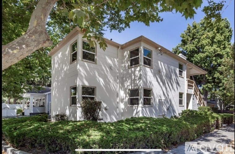 A white house with a tree in front.