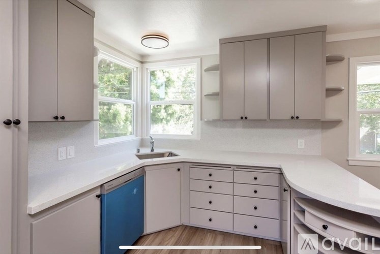 A kitchen with a blue trash can and white countertops.