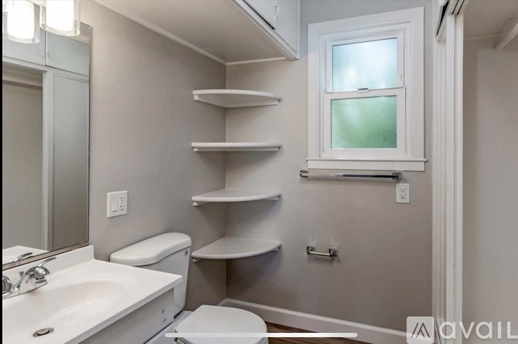 A bathroom with a white sink, toilet, and shelves.