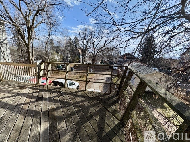 A wooden deck with a railing and a tree in the background.