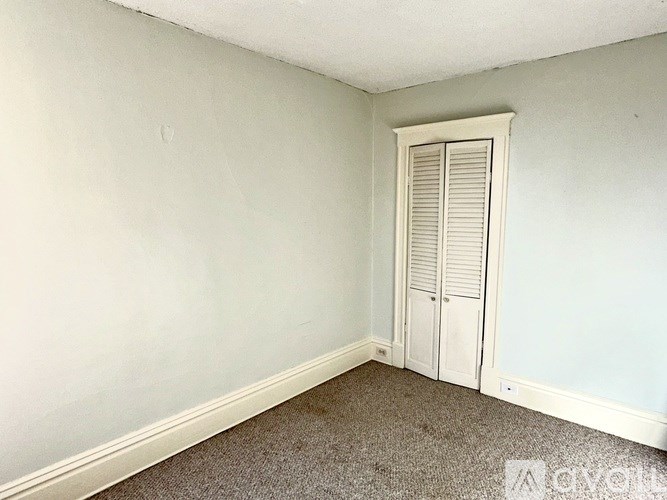 A room with a white door and carpeted floor.