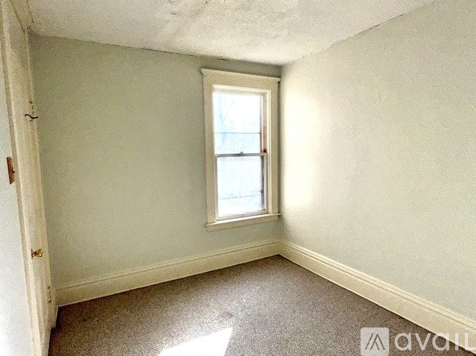 A room with a window and carpeted floor.