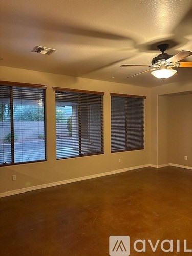 A room with a ceiling fan and two windows.
