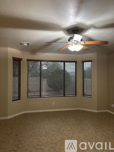 A room with a ceiling fan and three windows.