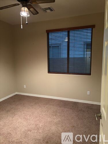 A room with a carpeted floor and a ceiling fan.
