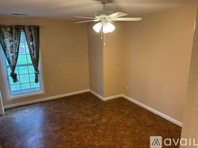 A room with a ceiling fan and a window with curtains.