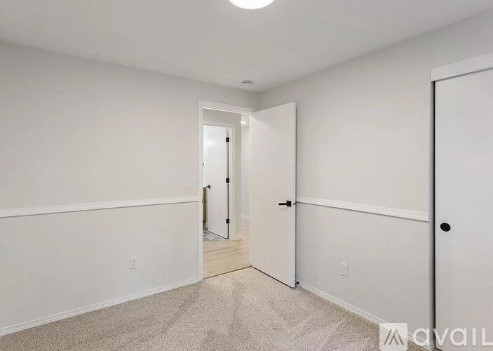A white hallway with a carpeted floor and a door on the right.
