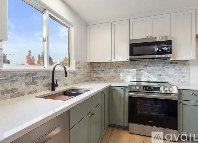 A kitchen with a stone backsplash and a window overlooking trees.