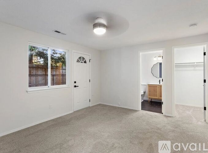 A spacious room with a carpeted floor and a large window with blinds.