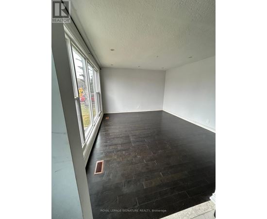 A room with a window and a wooden floor.