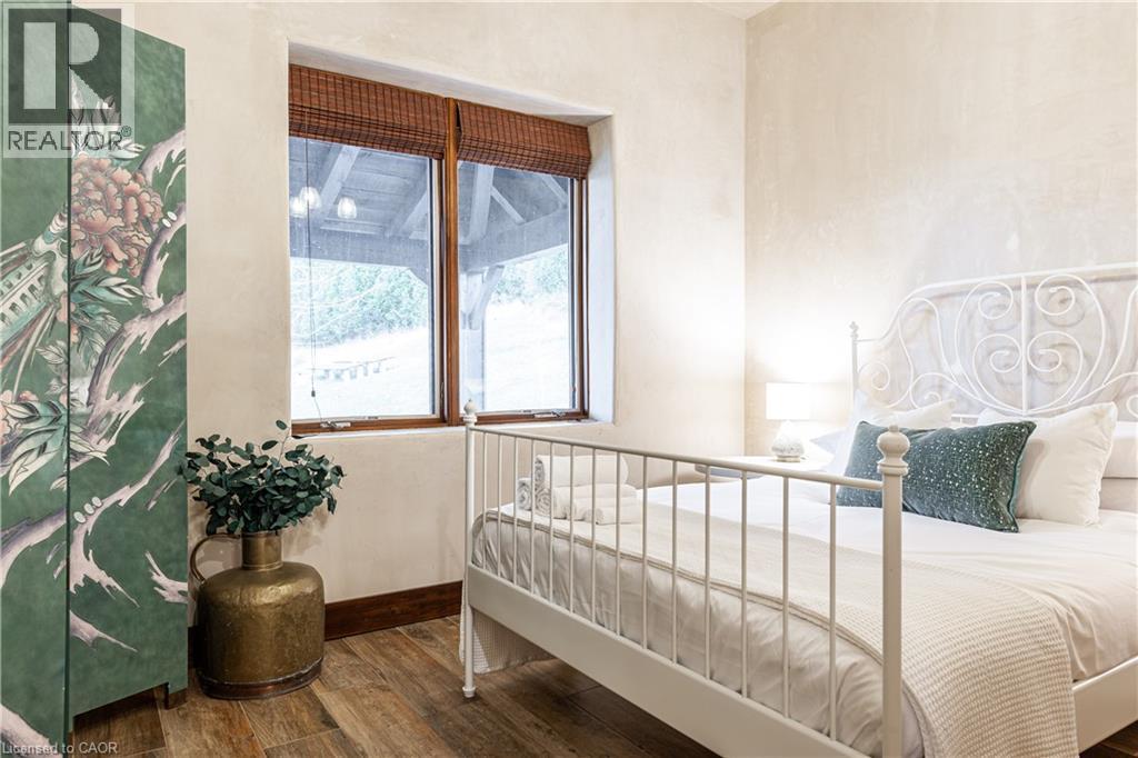 A bedroom with a white bed and a green plant on a table.