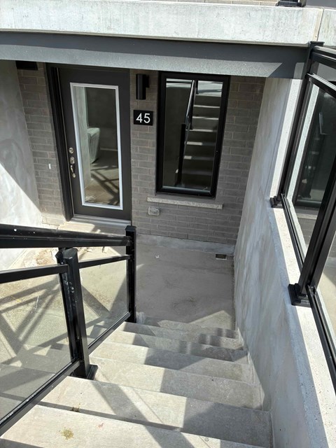 A staircase with a black railing and a glass door with the number 45 on it.