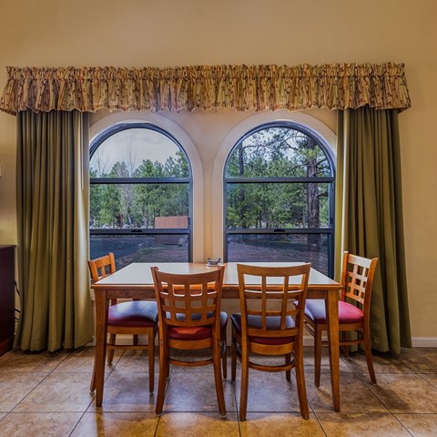 A dining room with a table and chairs in front of a large window.