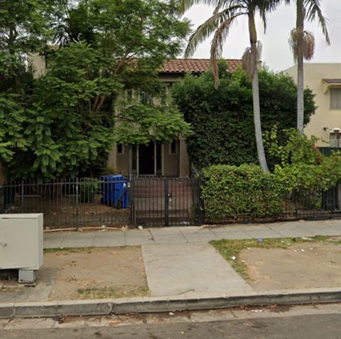 A house with a blue trash can in front of it.